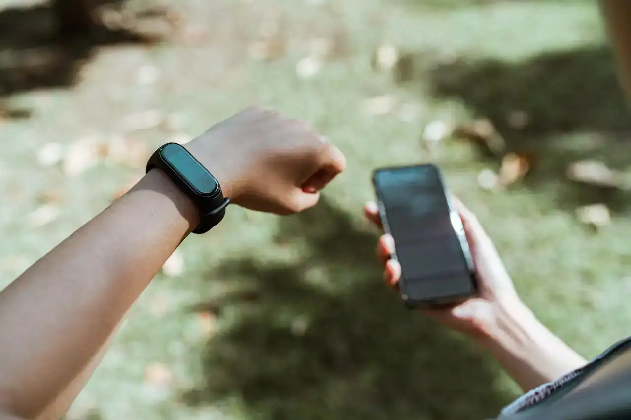 A user checks their best fitness smartwatch while also reviewing workout data on the companion smartphone app.